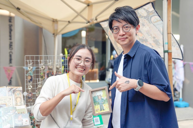 本屆主視覺插畫由青創品牌「異想之森」設計，以自然與想像為靈感，以溫暖筆觸描繪動植物故事，展現療癒與永續的生活美學。(照片圖右為林楷軒局長，圖左為異想之森負責人王佳薇)。