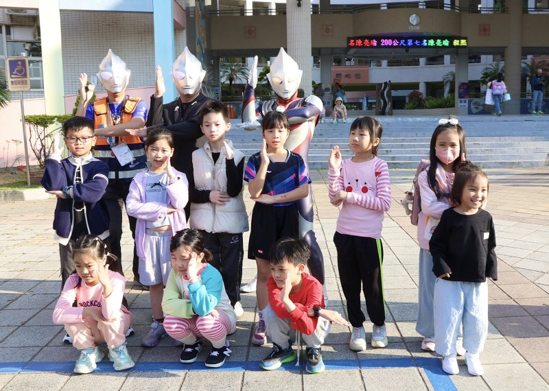 校長王彥嵓與家長會長、蘇守懌及師長家長扮演的超人力霸王，在校門口迎接學生開學。（漾新聞記者陳雯萍攝）