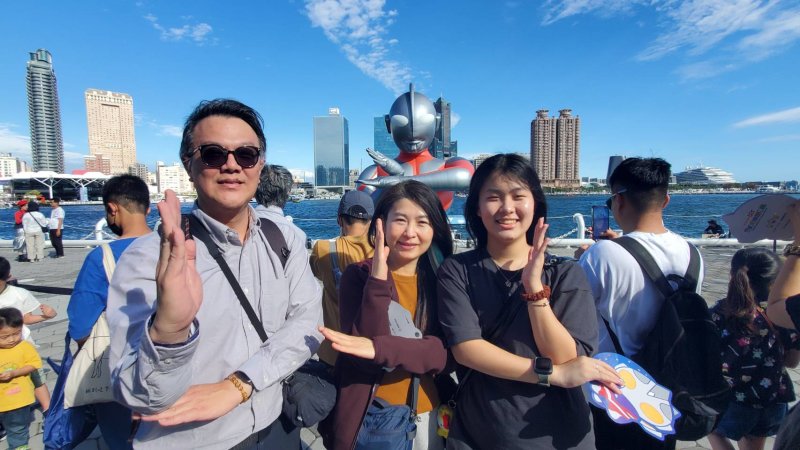 民眾kuso 擺出經典手勢與超人力霸王合影。圖為七賢國小榮譽家長會長何性翰一家，把握最難得時間，送別超人力霸王。(漾新聞記者陳雯萍攝)