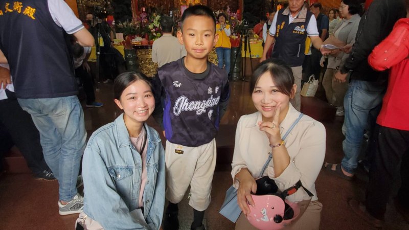 鳳山區忠孝國小十歲童林品翰連續博出14個聖杯，也吸引不少民眾爭相合影，希望分享他的好運氣。(漾新聞記者陳雯萍攝)