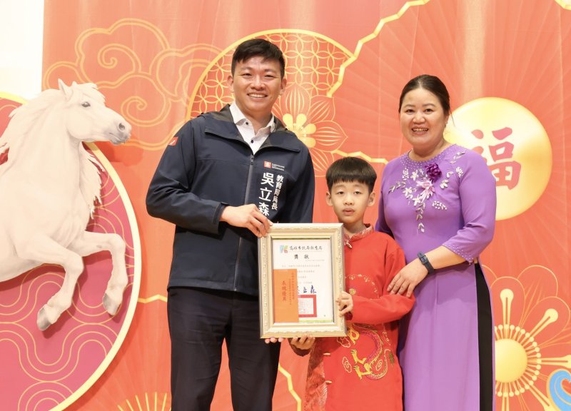 越南語教學支援老師武綺綿（右一）來台22年，指導許多學生學習越南語，愛上越南語之美，並參與競賽得獎。指導獲獎的學生，接受教育局長吳立森（左）頒獎表演。