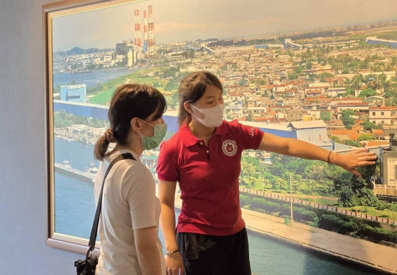 去年參加暑期工讀的學生（右），於紅毛港文化園區展示館大圖前向日本遊客進行導覽說明。