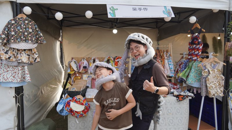  青年局長林楷軒（右）與青創品牌「呆手作」店家小幫手一同裝扮成恐龍造型合影，逗趣畫面讓現場笑聲不斷。