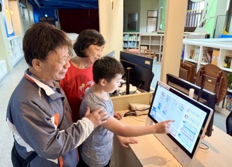 曹公國小在校園共讀站建置導入「AI智慧閱讀機」，小朋友協助社區長輩了解如何操作「AI智慧閱讀機」，成為連接社區與世代情感的溫馨空間。