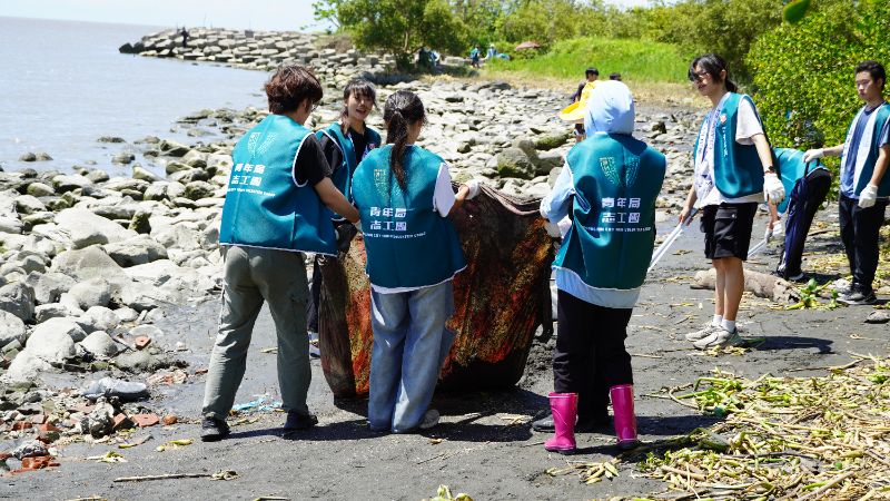 青年志工不畏烈日，沿著海岸線撿拾垃圾及海洋廢棄物。